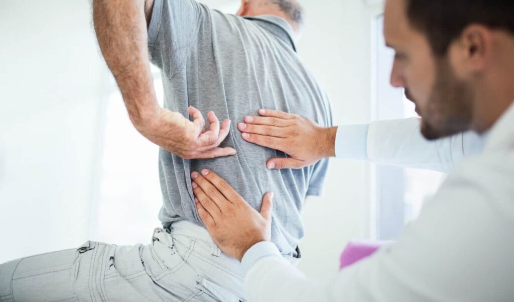 Acuerdos Por Lesiones De Disco Abultado O Herniado En Accidentes 1 Un Médico Examina La Espalda De Un Paciente Después De Un Accidente Con Lesiones Personales.