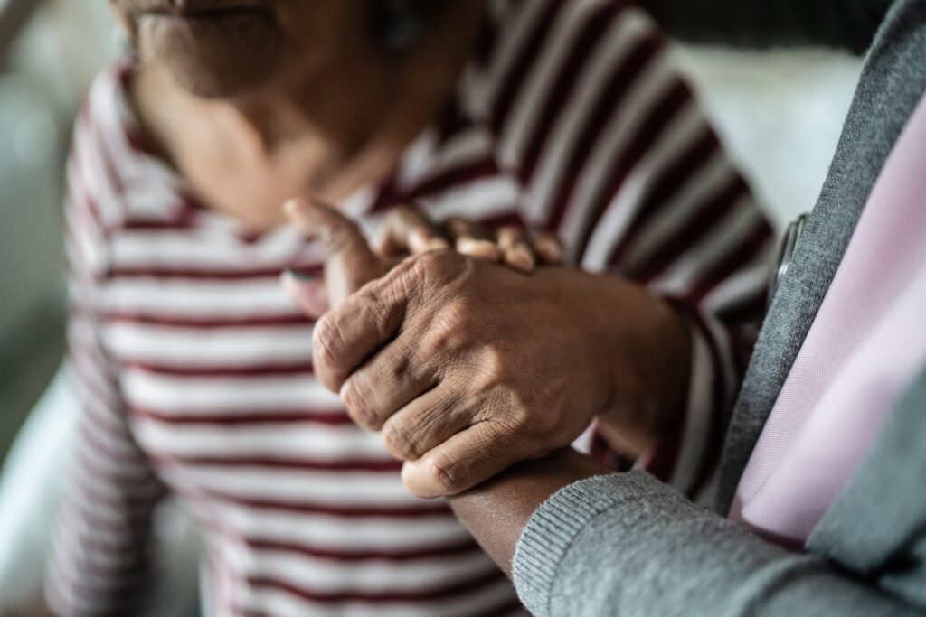 nursing home worker holding hand of elderly woman