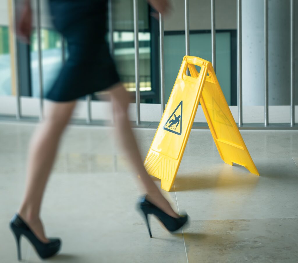yellow warning slip and fall sign with lady walking by
