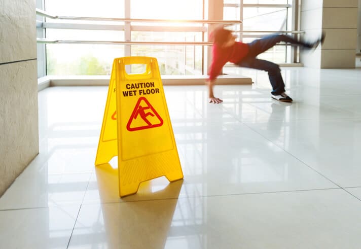 Person Falling Next To Slip and Fall Accident Sign