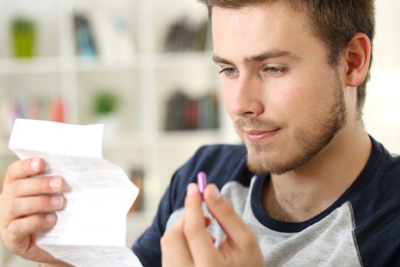 Men taking a prilosec pill while reading a note
