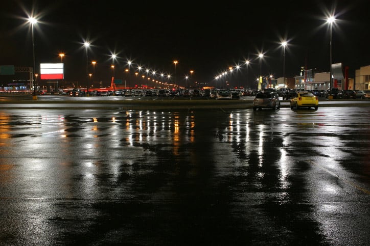 A dark parking lot that is wet after raining, creating a risk for a slip-and-fall accident.