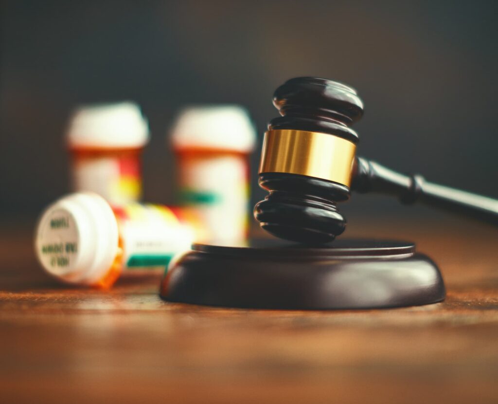 picture of a gavel next to bottles of pills