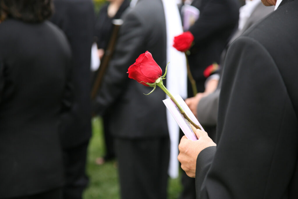 person holding a rose at a funeral
