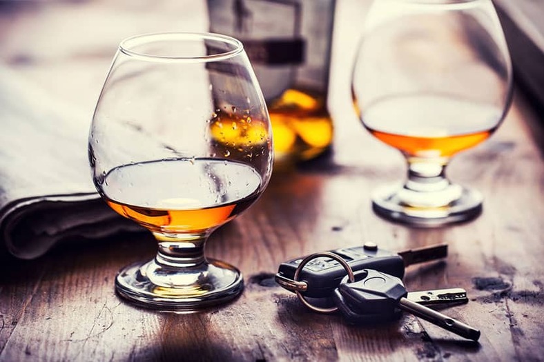 car keys next to glasses filled with liquor on a table