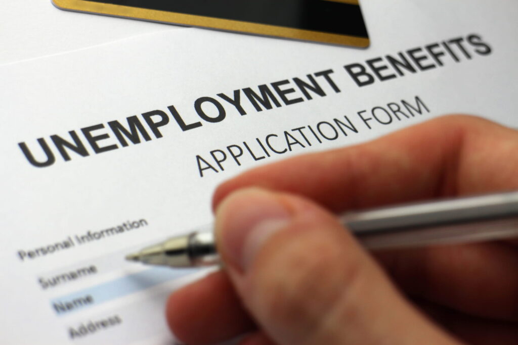 person filling out unemployment benefits application form