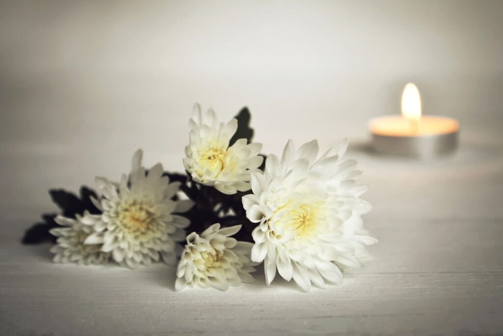 White flowers and a lit candle in memorial of a wrongful death.
