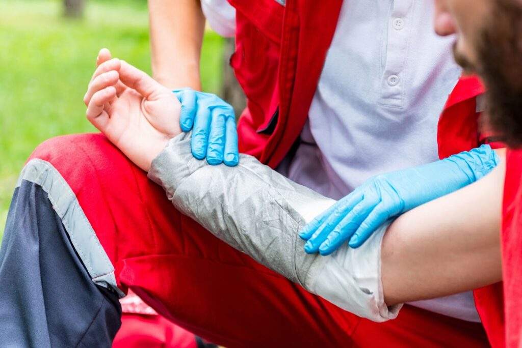 A person receiving medical treatment on their arm after being burned. Medical personnel with blue gloves is wrapping the injured arm.