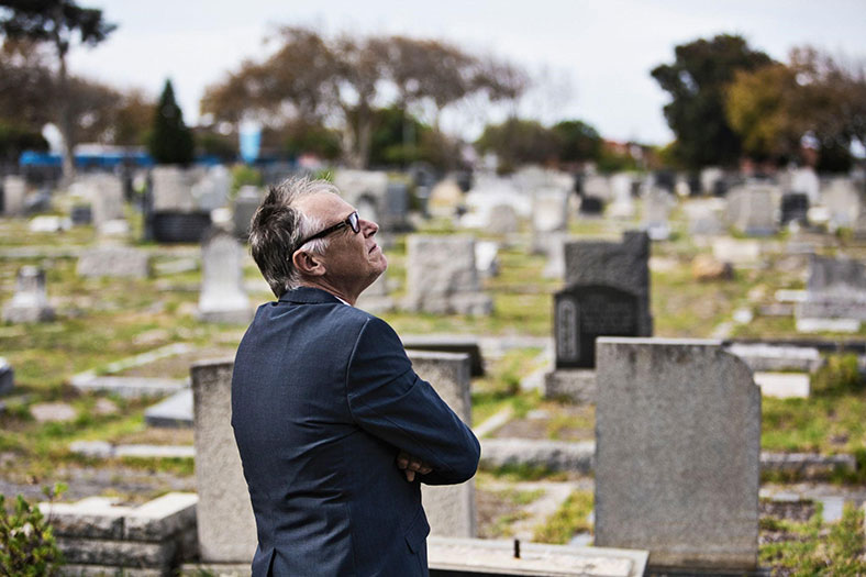 man stands in front of graves at a cemetery