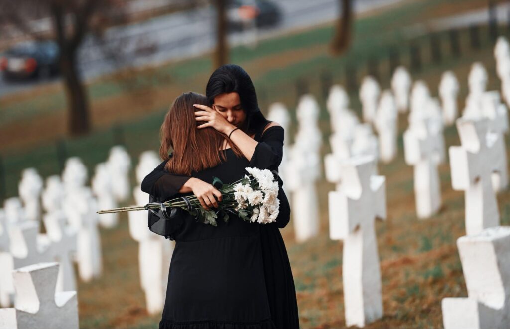 two woman hugging each other at a funeral