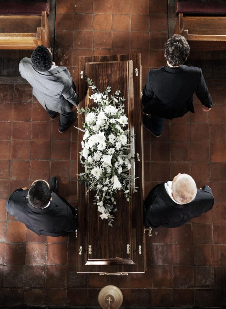 4 men  carrying a coffin at a funeral