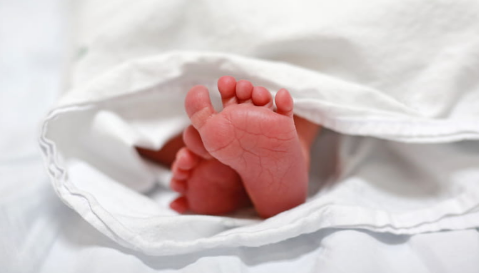 a newborn baby's foot peeking out of a white blanket