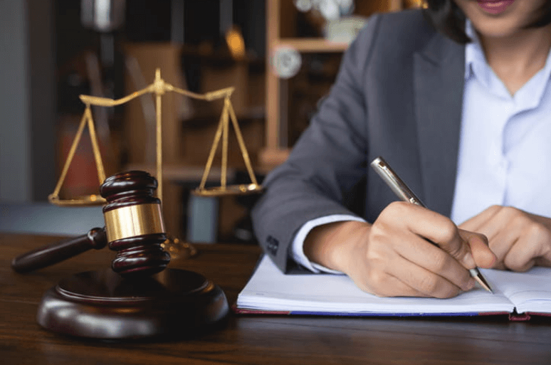 a sexual assault lawyer signing paperwork next to a gavel and the scales of justice