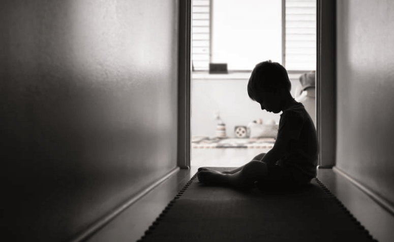 a silhouette of a sad sexually abused child, sitting in a hallway.
