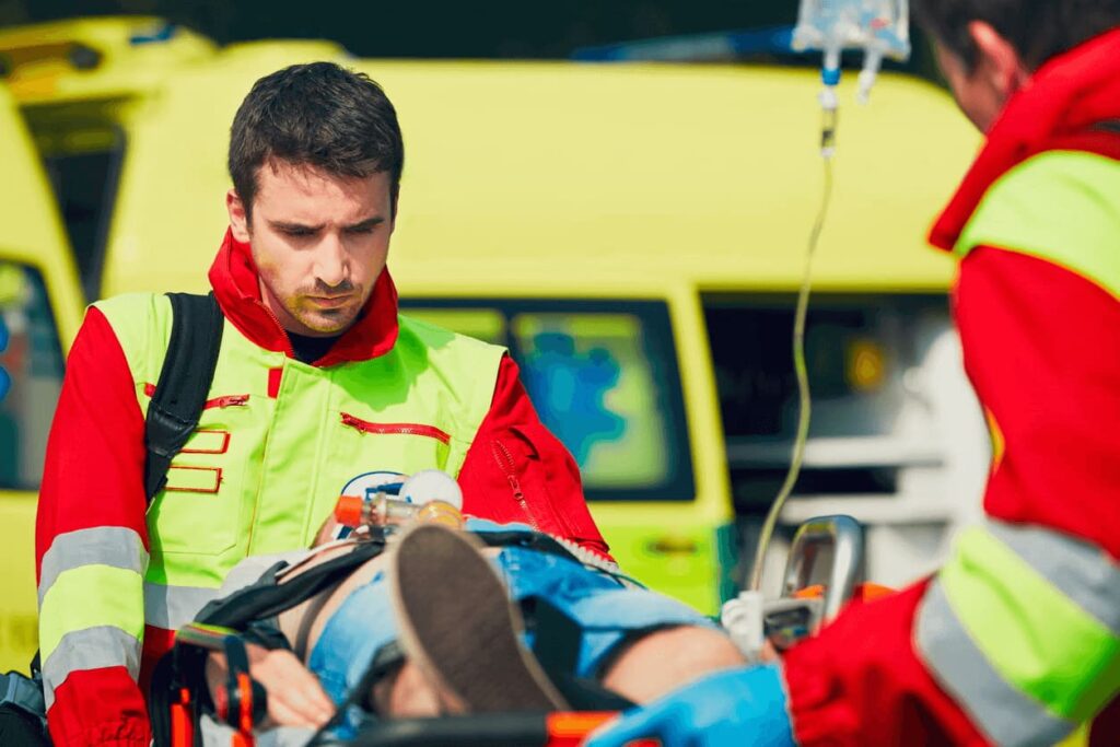 Two medics treat an individual strapped to a stretcher after suffering a catastrophic injury
