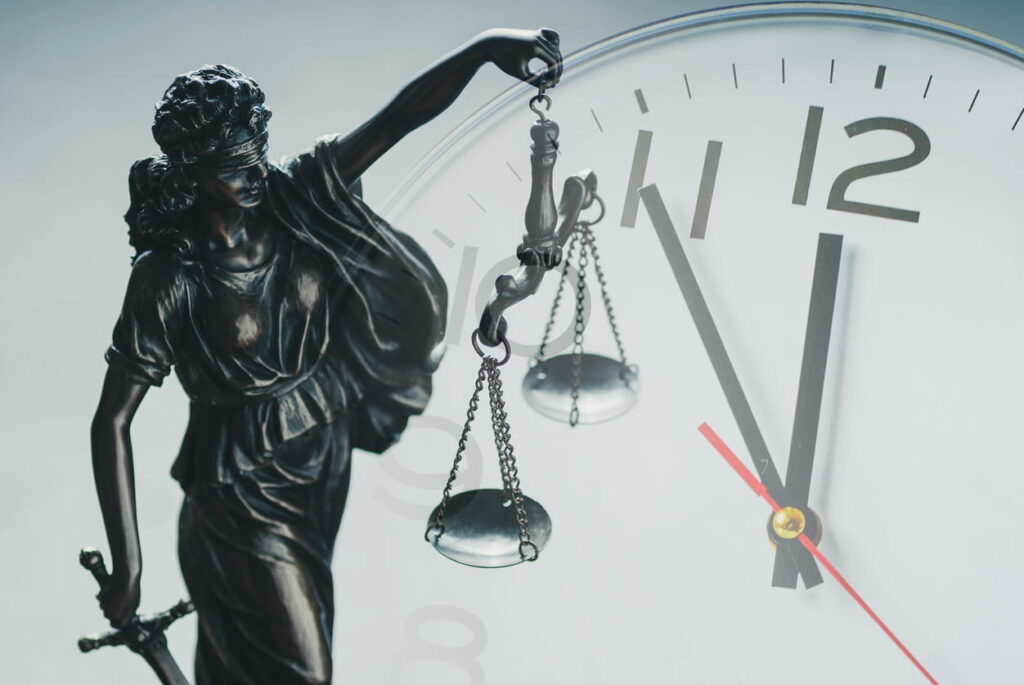 A Lady Justice statue in front of a clock.
