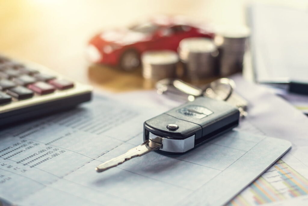 A set of car keys and a calculator overtop a medical bill when determining a car accident settlement amount.