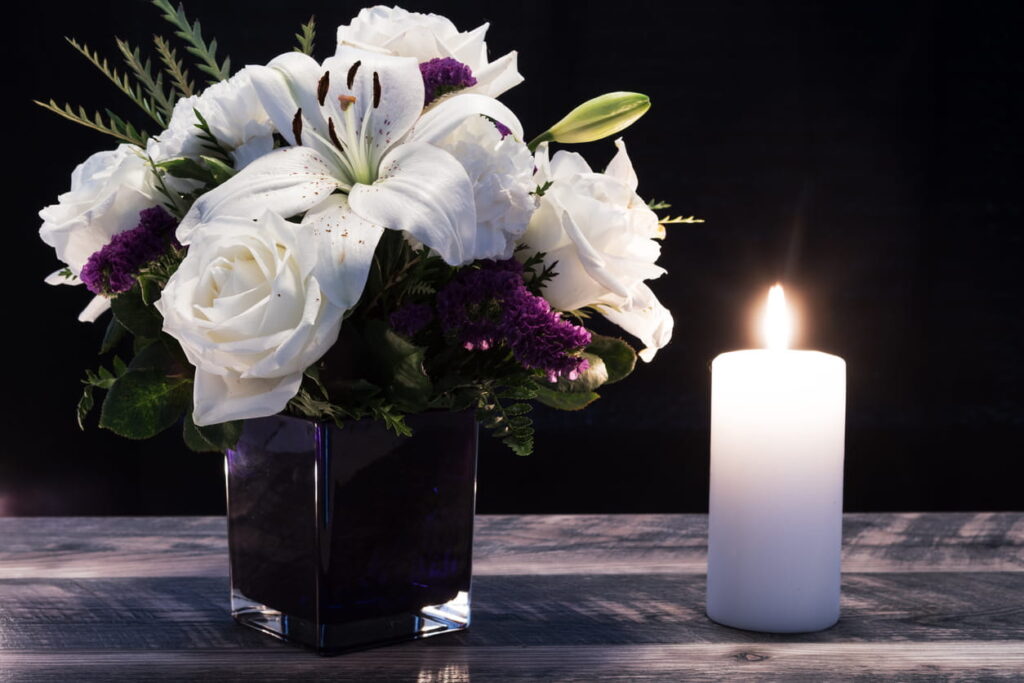 White flowers and a candle lit in memorial to a wrongful death.