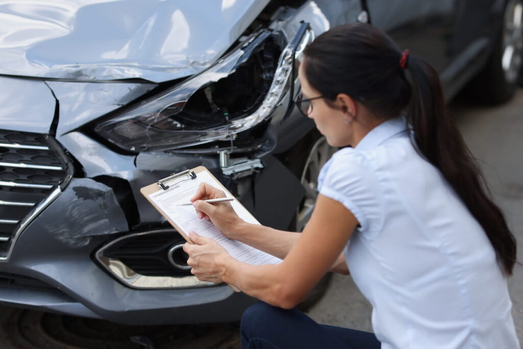 A claims adjuster inspecting the damage of a car after a car accident to determine fault.
