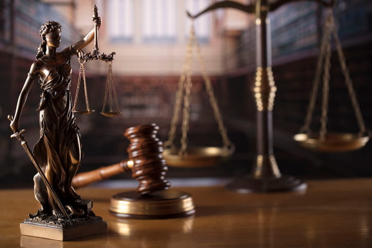 A Lady Justice statue next to a gavel and the scales of justice. 