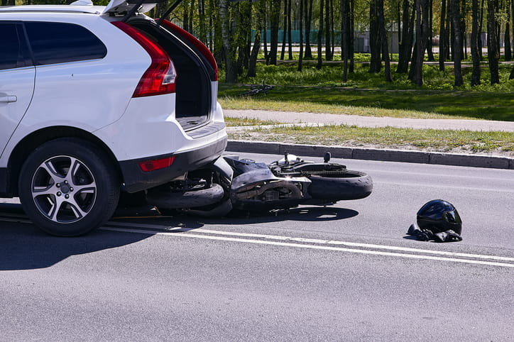 A motorcycle on the roadway after being struck by a white SUV. 