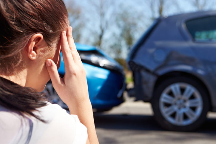 A woman holds her head in frustration while she looks on at a chain reaction car accident. Photo shows two vehicles in the chain. 