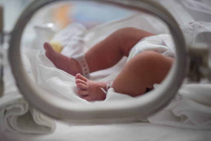 The focus is on a newborn's legs while they are in the hospital. 