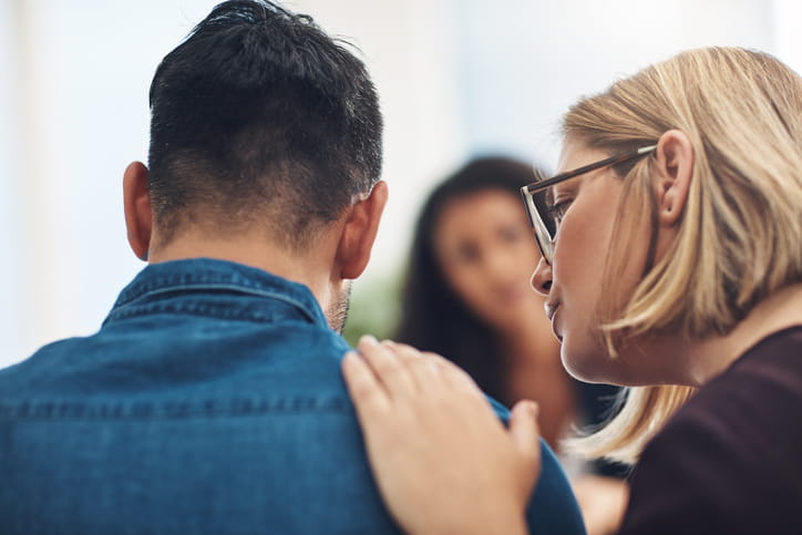 A woman comforts a man after he experiences the wrongful death of a loved one. 
