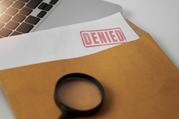 A piece of paper inside an envelope that reads "denied" in red letters. 