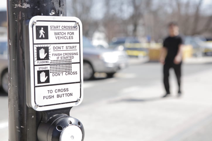 Focus is on the instructions posted at a crosswalk for pedestrians.