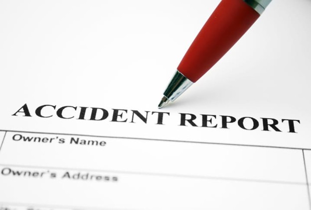 A pen poised above an Accident Report form.