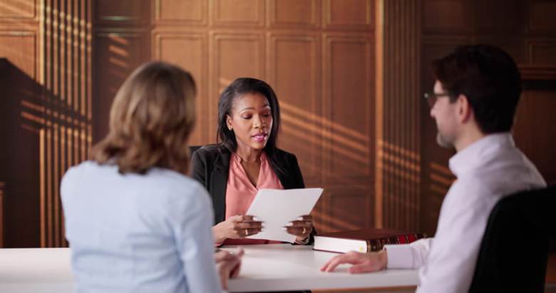 A mediator speaks with two clients during a meeting.