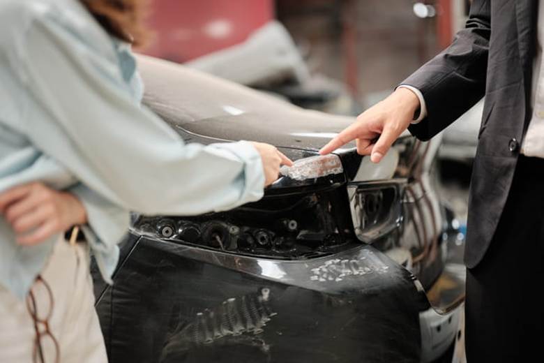 Two people looking at the crumple zone of a vehicle after an accident.