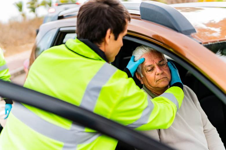 A paramedic inspects a victim's head after he's been in a car accident.