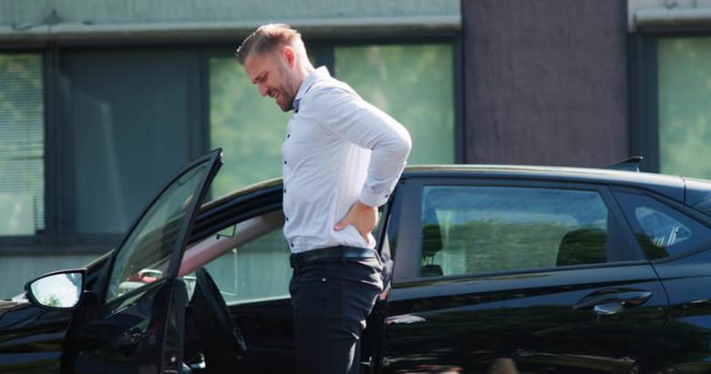 A man holds his back in pain after a car accident.
