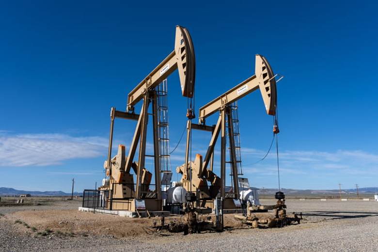 Two working oil pump jacks against the blue sky in Colorado.