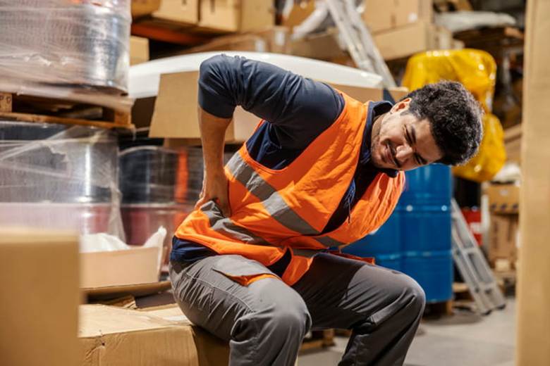 A worker holds his back while in pain after an injury.